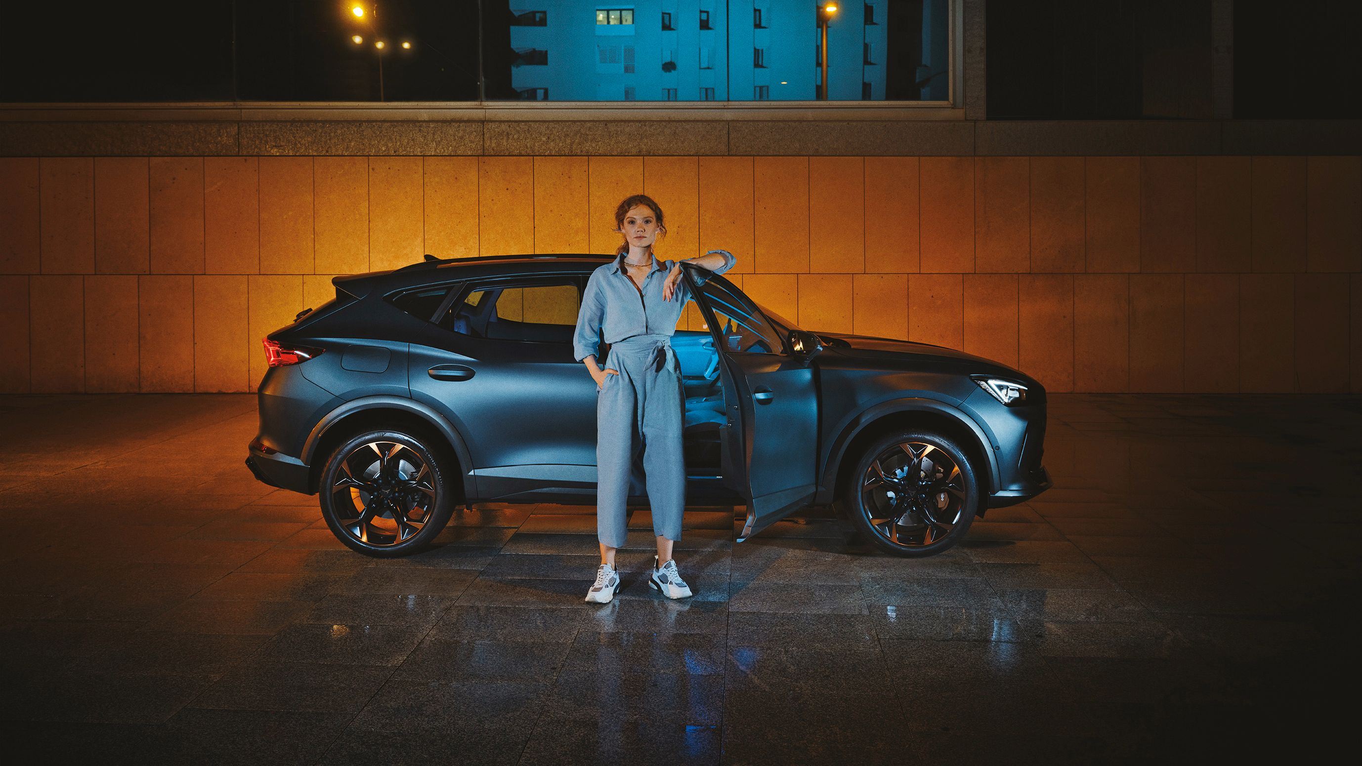 CUPRA Formentor bei Nacht, eine Frau steht davor