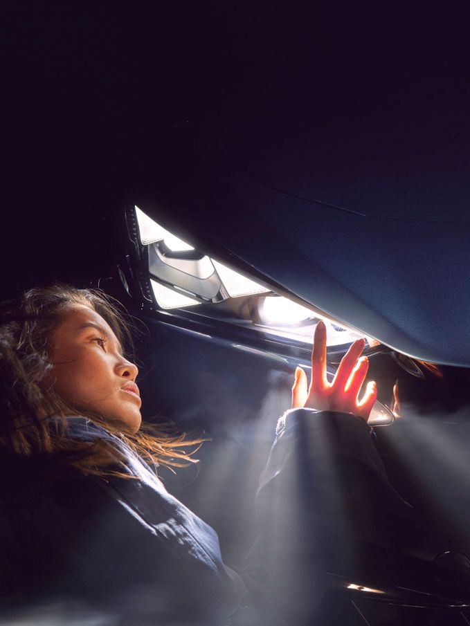 Eine Frau berührt den leuchtenden Scheinwerfer eines CUPRA Tavascan.