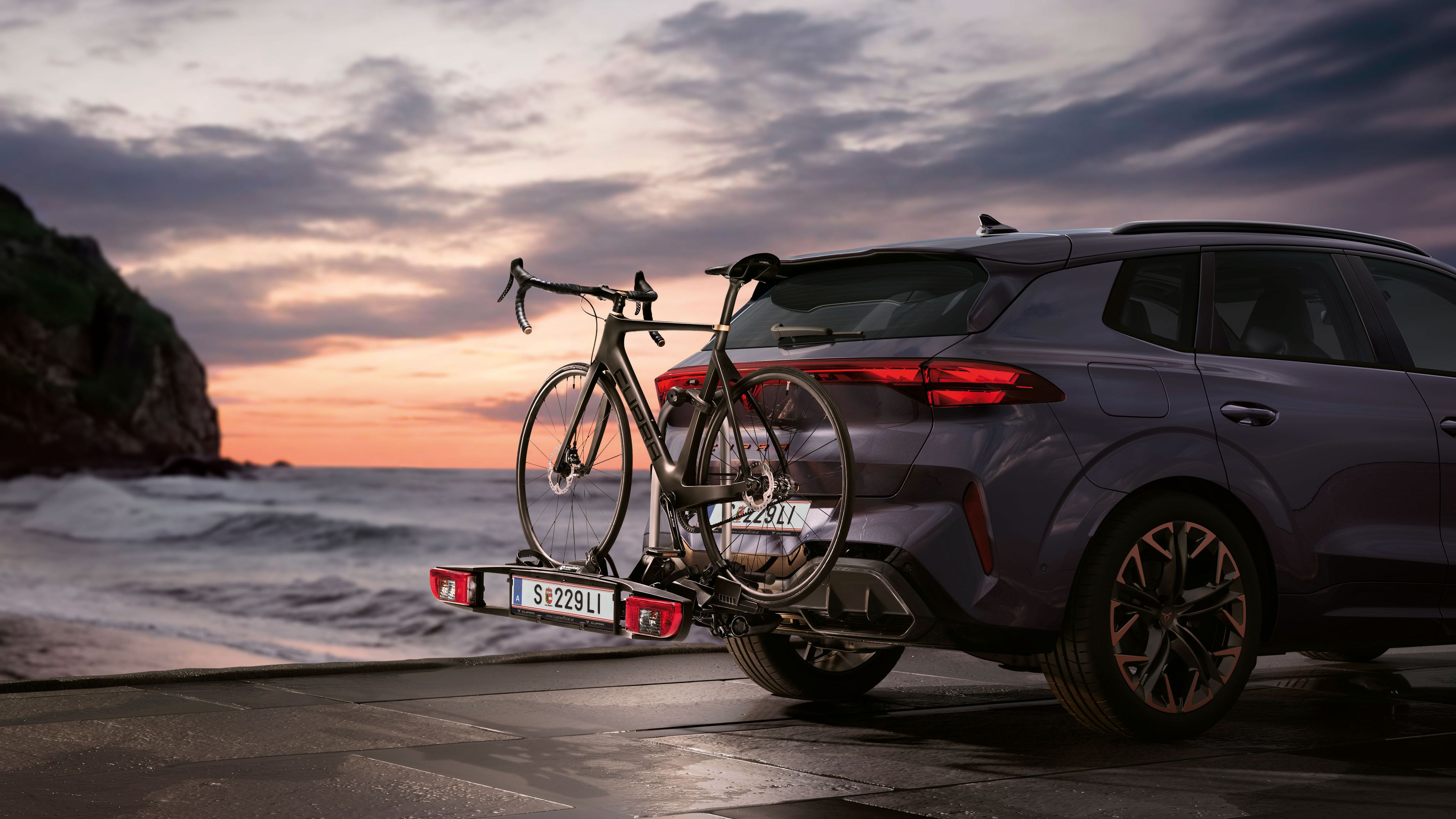 Ein CUPRA Terramar mit Fahrradheckträger parkt an der Meeresküste.