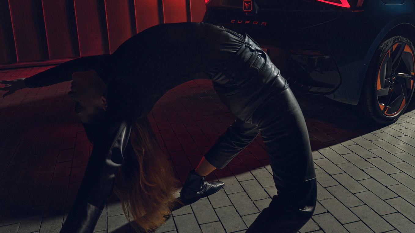 Eine Frau macht Gymnastik vor dem Born zu sehen in Heckansicht und beleuchtet.