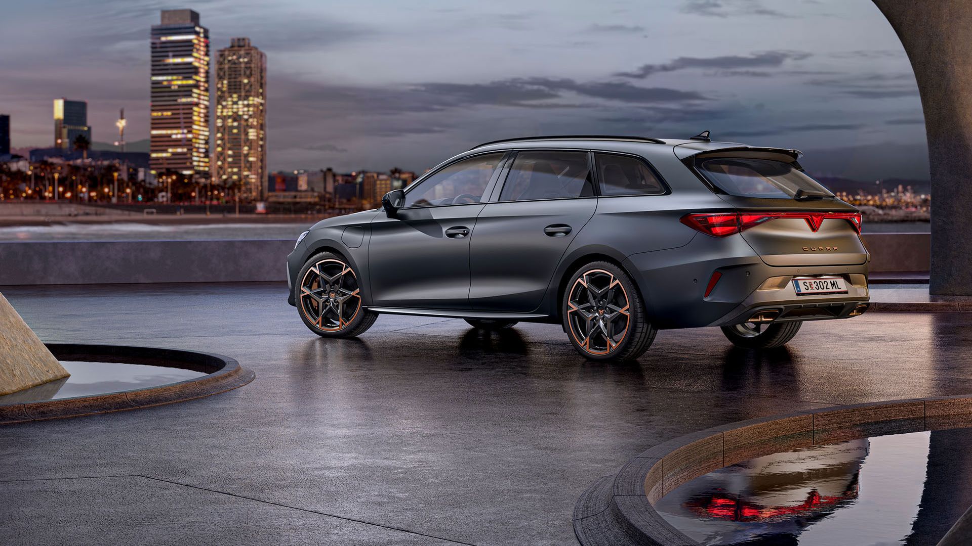 Seitliche Heckansicht eines grauen CUPRA Leon SP Kombi vor der Skyline einer Stadt.