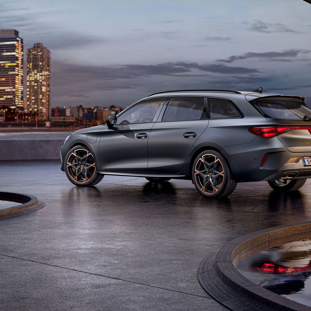 Seitliche Heckansicht eines grauen CUPRA Leon SP Kombi vor der Skyline einer Stadt.