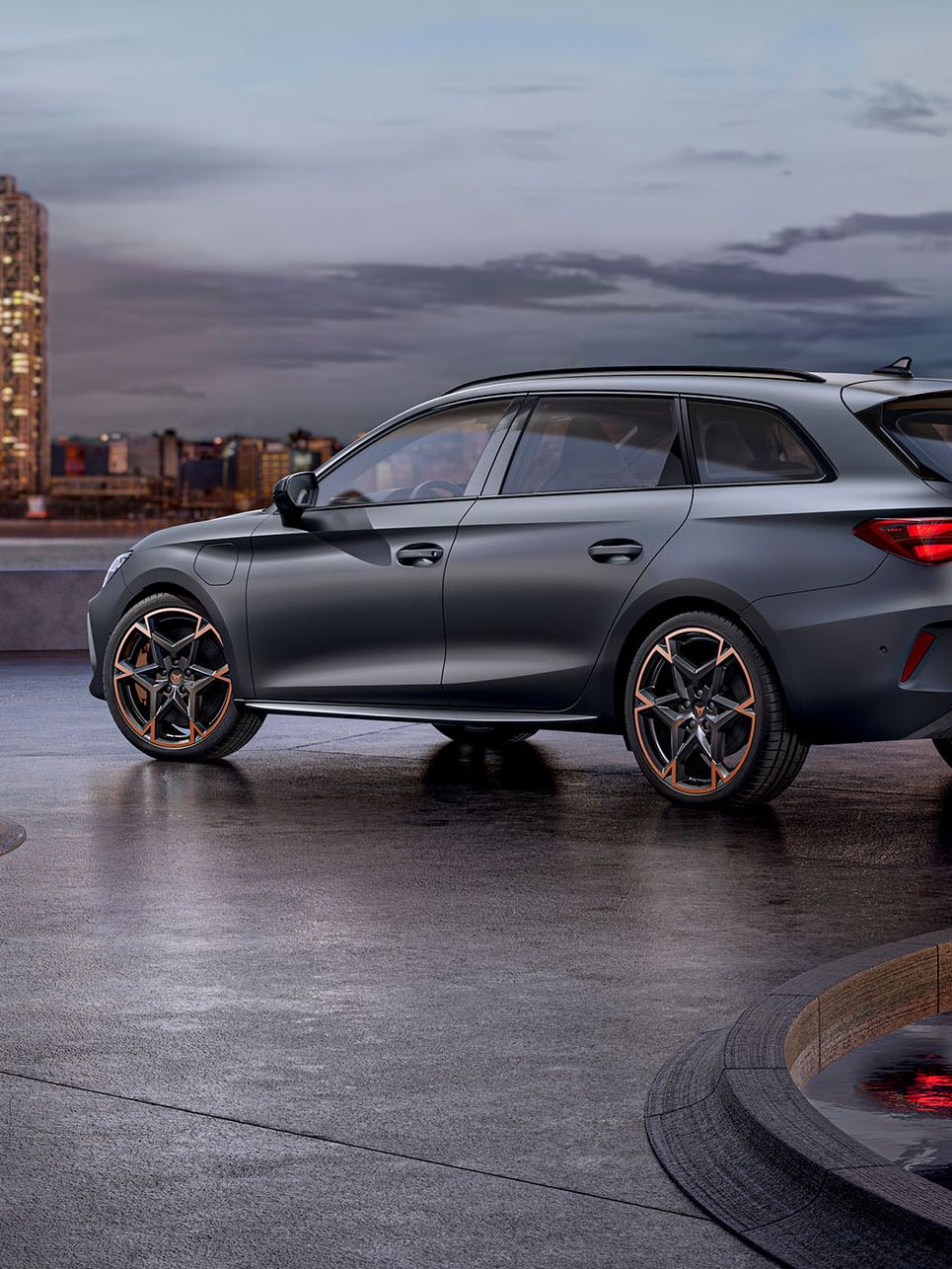 Seitliche Heckansicht eines grauen CUPRA Leon SP Kombi vor der Skyline einer Stadt.