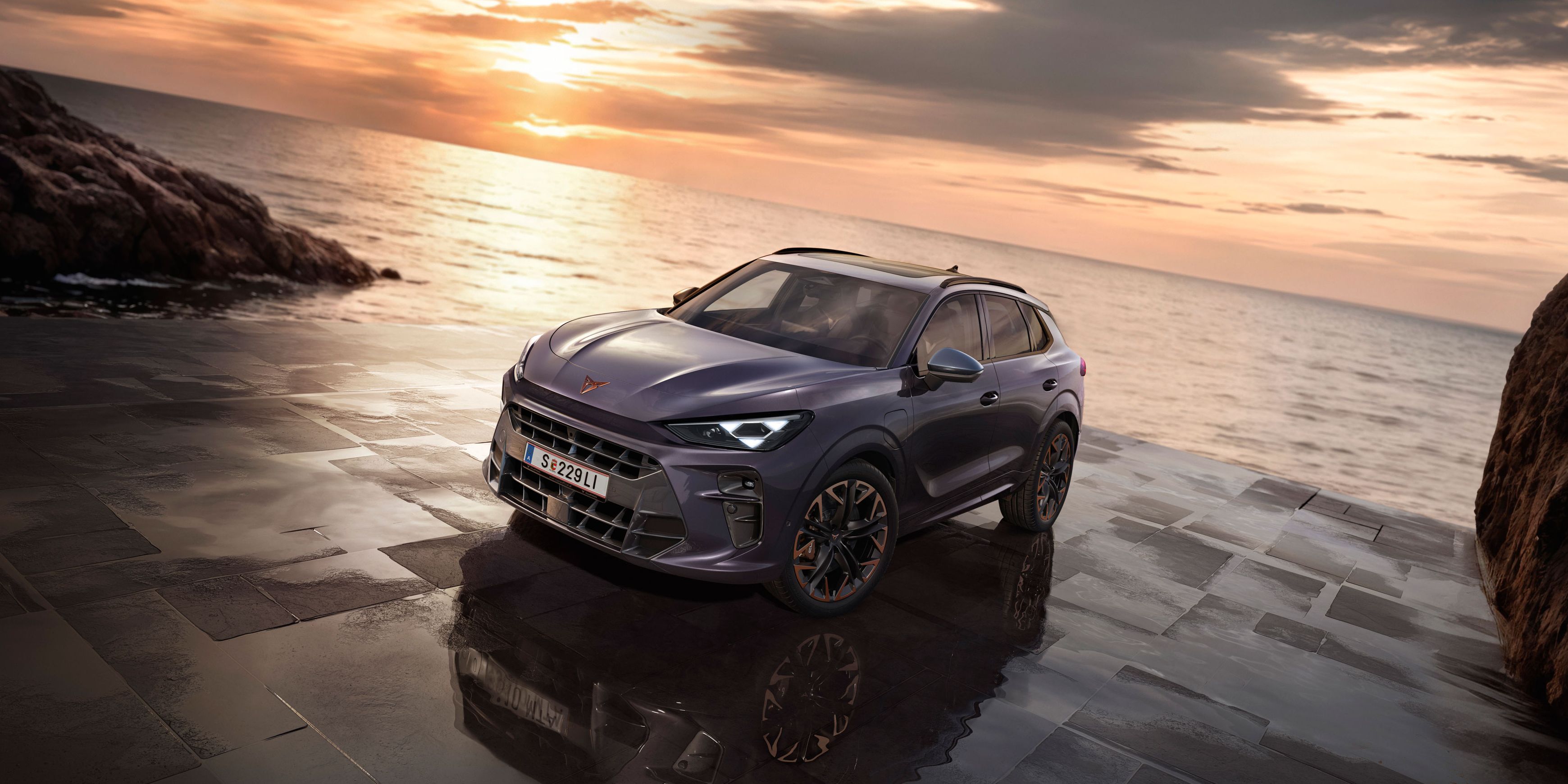 Ein CUPRA Terramar parkt zwischen Felsen an der Meeresküste.