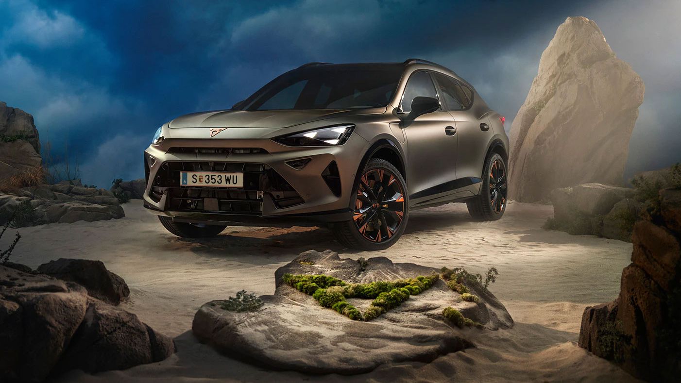 Ein CUPRA Formentor VZ in Bronze steht dramatisch beleuchtet in einer felsigen, nebeligen Landschaft. Eine Lichtstrahl beleuchtet das Fahrzeug und betont seine Konturen. Im Hintergrund sind Felsen und Pflanzen zu sehen.