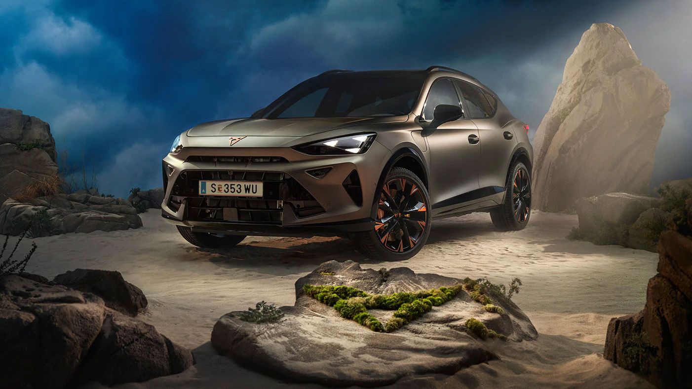 Ein CUPRA Formentor VZ in Bronze steht dramatisch beleuchtet in einer felsigen, nebeligen Landschaft. Eine Lichtstrahl beleuchtet das Fahrzeug und betont seine Konturen. Im Hintergrund sind Felsen und Pflanzen zu sehen.