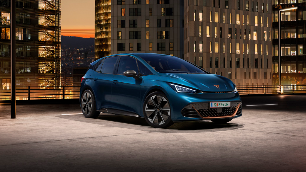 Ein blauer CUPRA Born auf dem Dach eines Parkhauses. Im Hintergrund beleuchtete Gebäude bei Nacht.