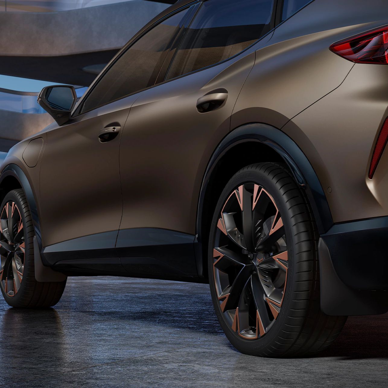 Ein CUPRA Formentor in einer Garage, mit Detailansicht auf die Hinterräder und Schmutzfänger. Das Fahrzeug ist in Bronze lackiert. Im Hintergrund sind architektonische Strukturen und eine Stadtlandschaft bei Dämmerung zu sehen.