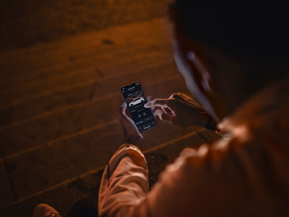 Mann mit Smartphone in der Hand verbunden mit der CUPRA Charging app 