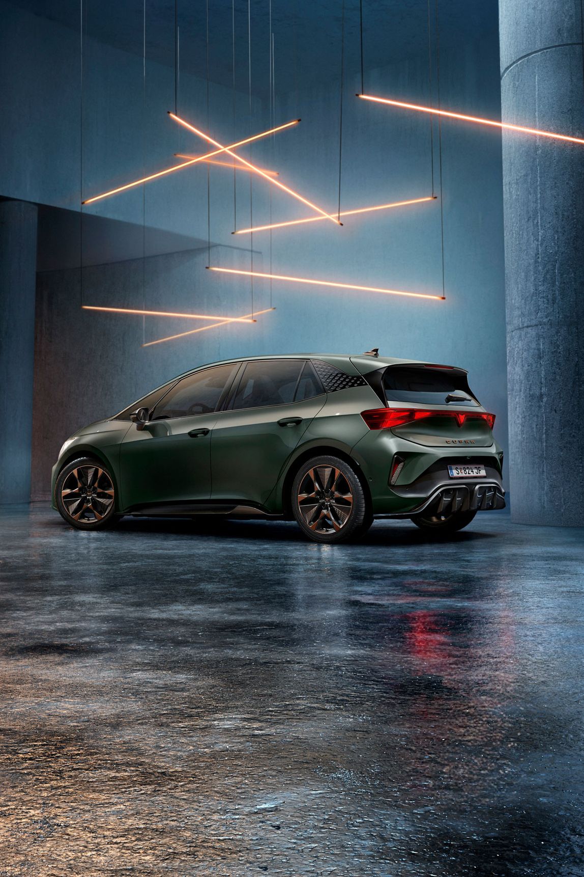 Ein grüner CUPRA Born steht in einem düsteren, industriellen Ambiente mit großen Säulen. Über dem Auto hängen stilvolle, leuchtende LED-Lichter in geometrischen Formen. Der Boden ist glatt und reflektiert das Licht leicht.
