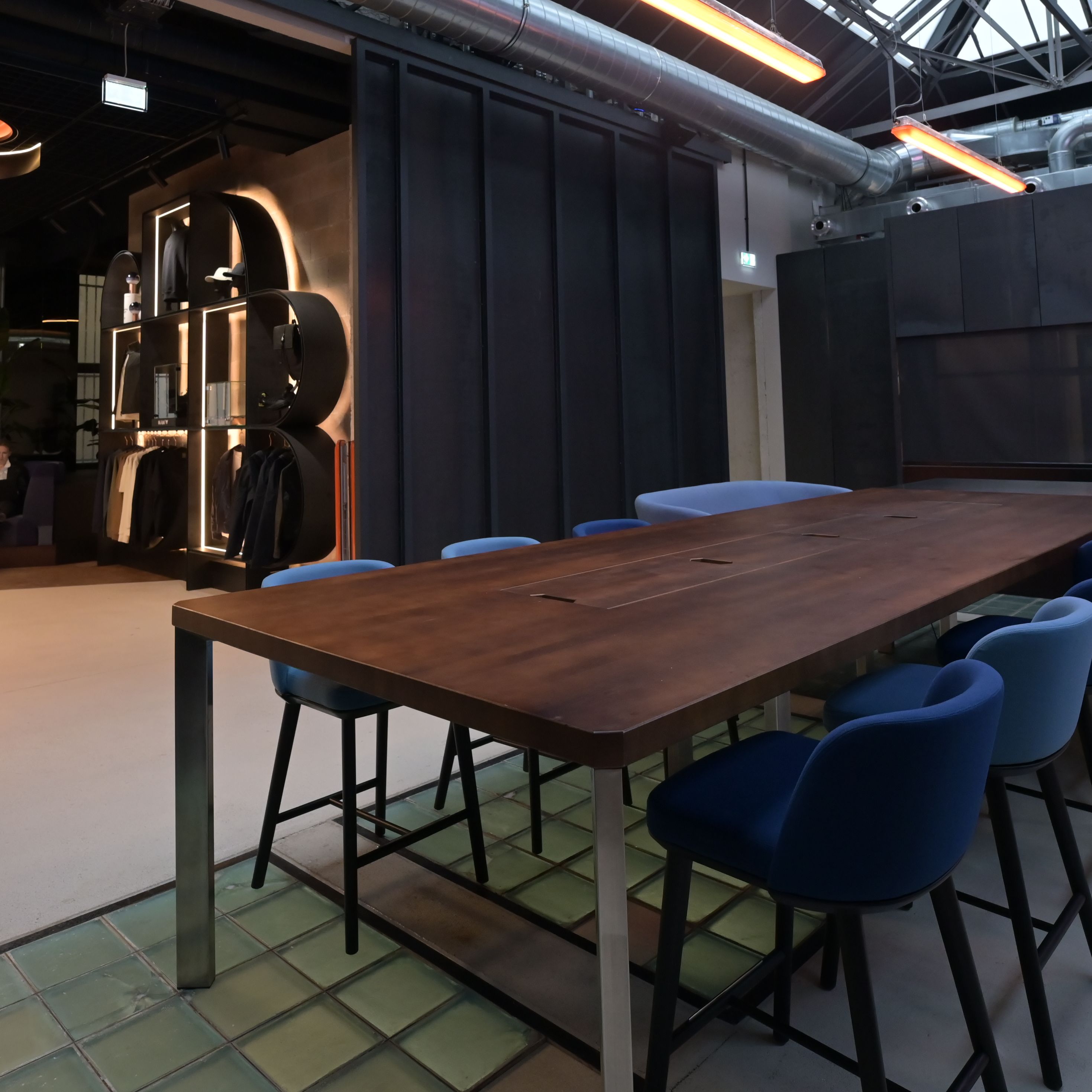 Konferenzraum mit langem Bartisch, passenden Barhockern und integrierter Küchenzeile sowie Blick auf die Businesslounge 