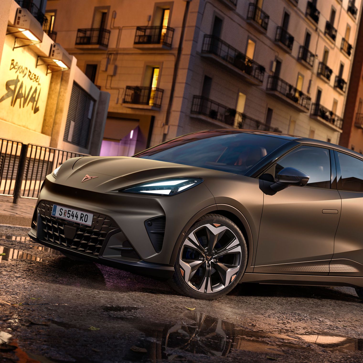 CUPRA Raval in Mangan-Grün steht auf einer Straße in urbaner Umgebung