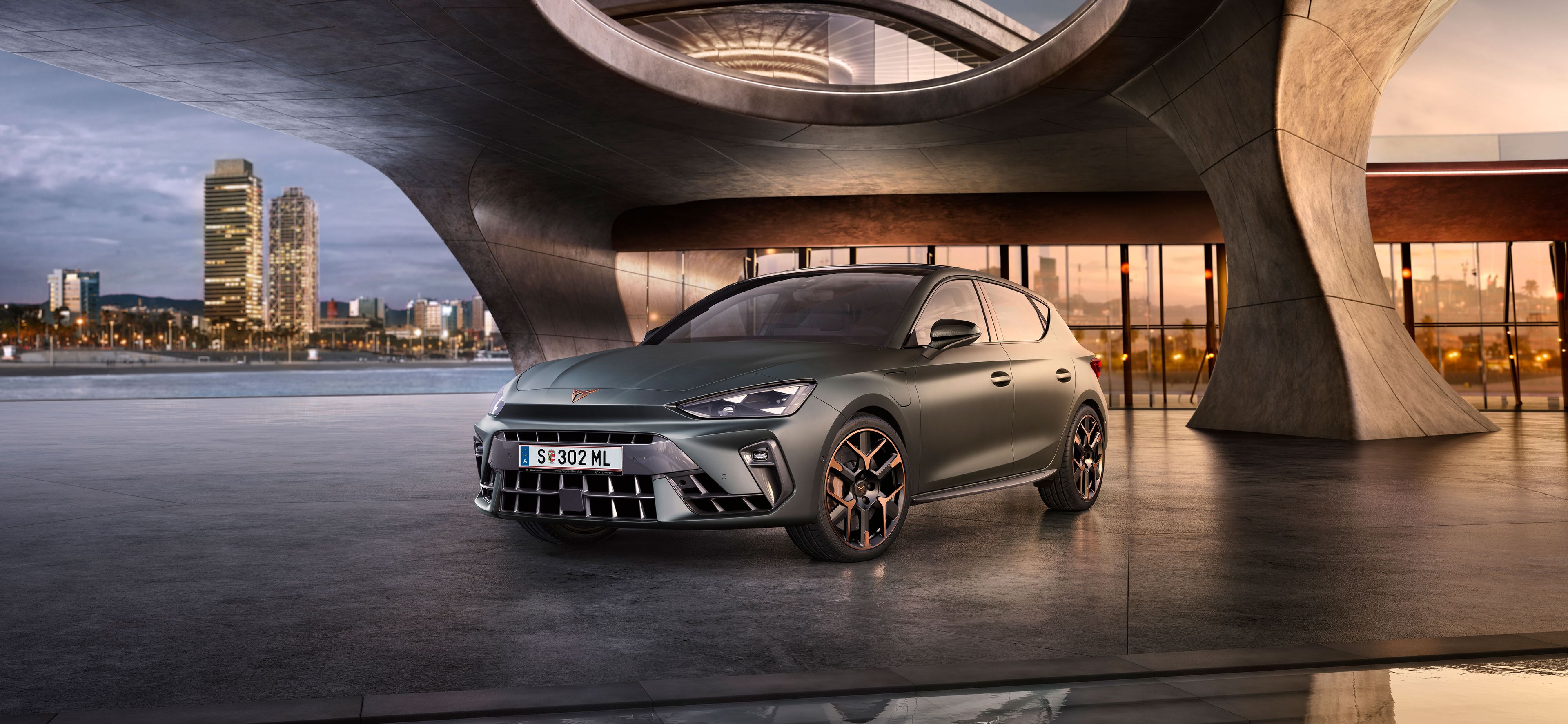 Schräge Vorderansicht eines grauen CUPRA Leon, der in einem modernen Parkhaus parkt.