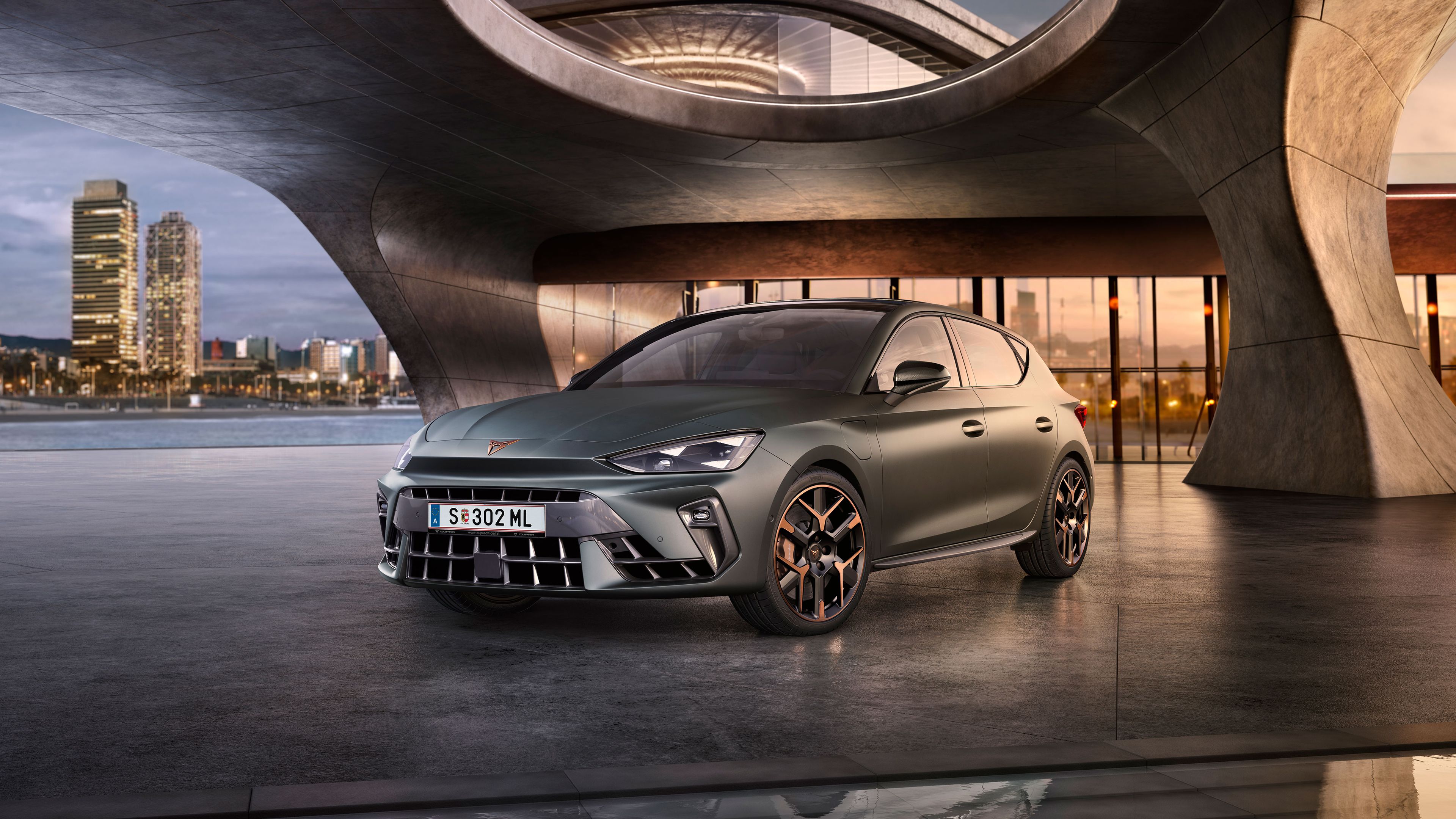 Schräge Vorderansicht eines grauen CUPRA Leon, der in einem modernen Parkhaus parkt.