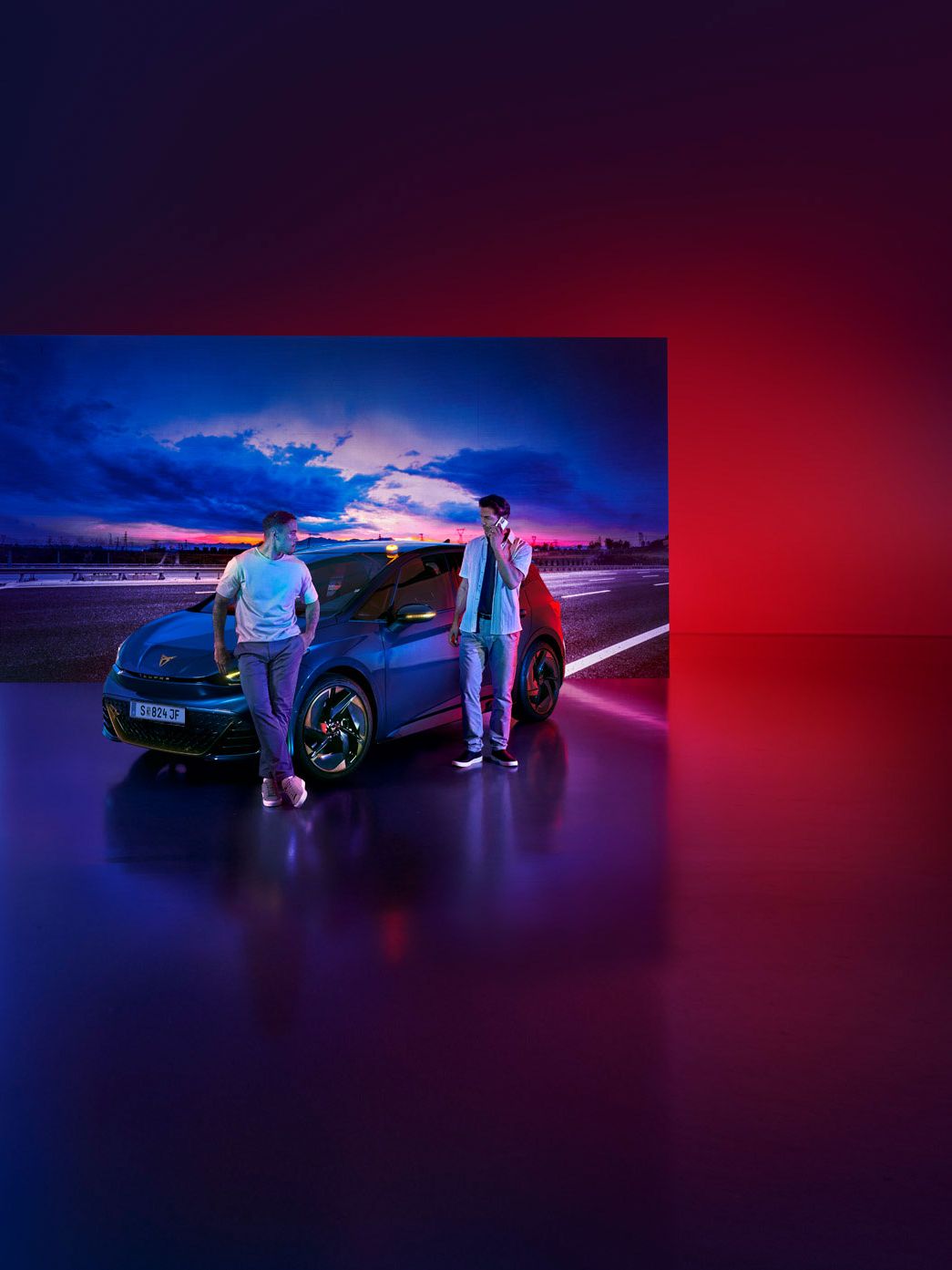 Ein Mann lehnt an einem CUPRA Born, ein anderer Mann steht daneben und telefoniert.