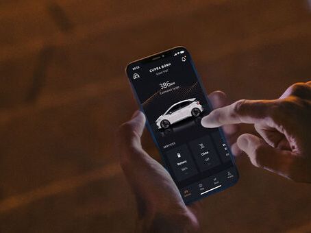 Eine Person sitzt nachts auf Treppenstufen und nutzt CUPRA Connect auf einem Smartphone.