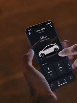 Eine Person sitzt nachts auf Treppenstufen und nutzt CUPRA Connect auf einem Smartphone.