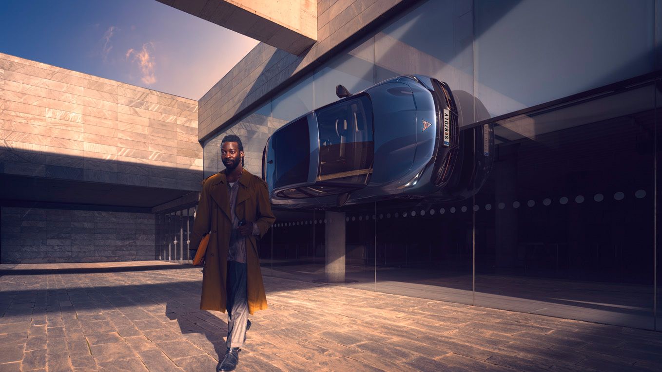 CUPRA Tavascan seitlich an der Wand befestigt mit Mann im Vordergrund