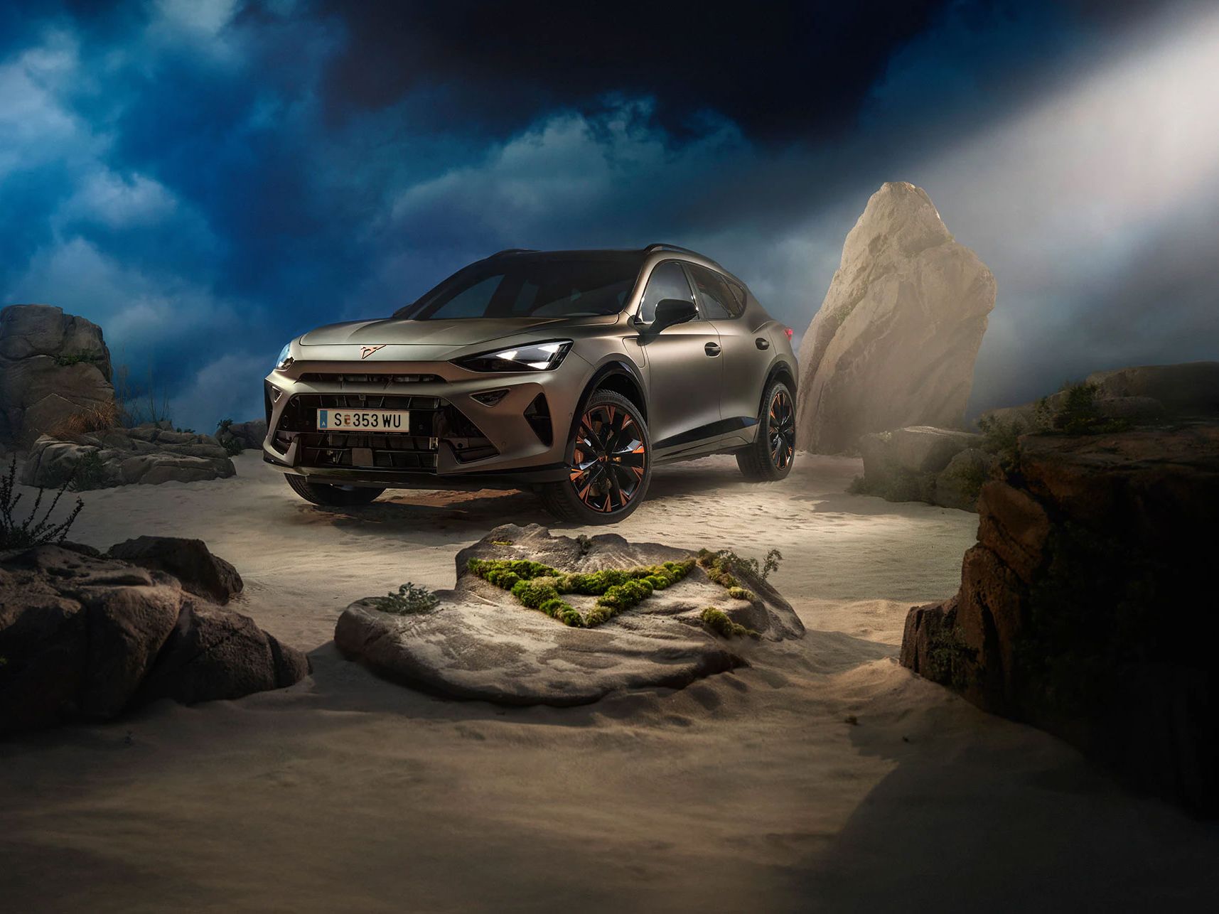 Ein CUPRA Formentor VZ in Bronze steht dramatisch beleuchtet in einer felsigen, nebeligen Landschaft. Eine Lichtstrahl beleuchtet das Fahrzeug und betont seine Konturen. Im Hintergrund sind Felsen und Pflanzen zu sehen.