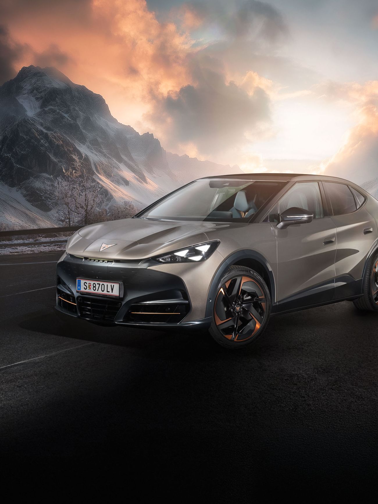 Ein bronzefarbener CUPRA Tavascan auf einer winterlichen Bergstraße.