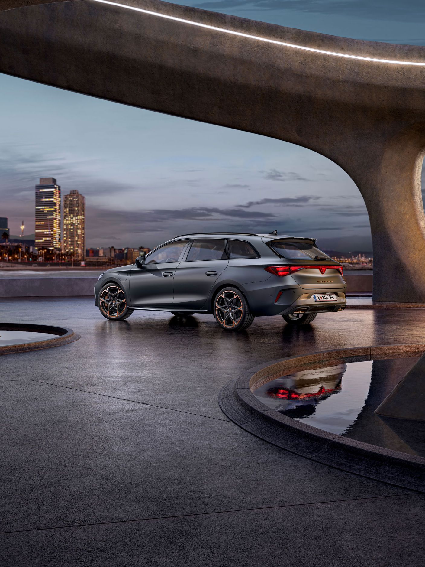 Schräge Seitenansicht von Hinten auf einen grauen CUPRA Leon Sportstourer in einem modernen Parkhaus.