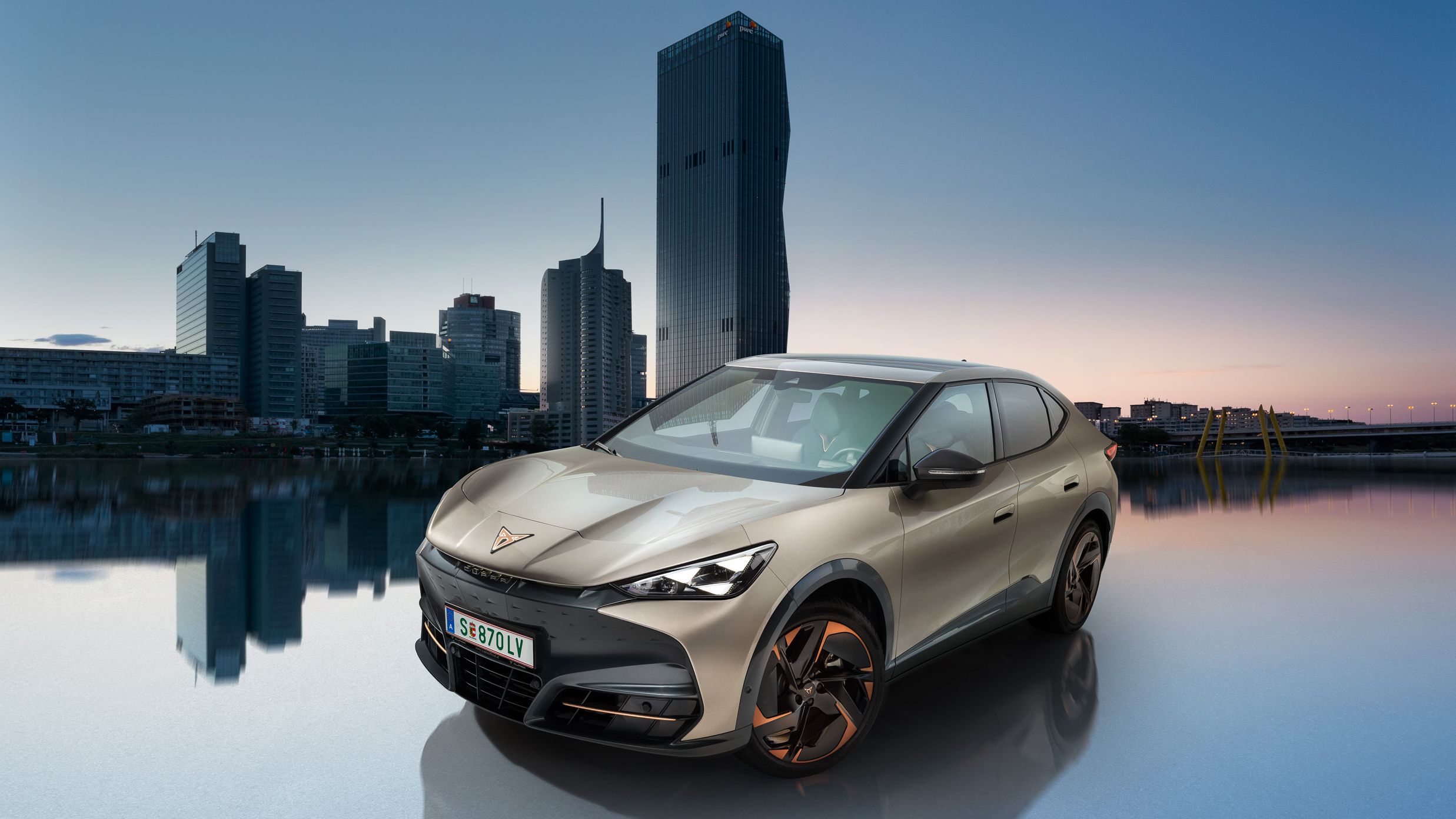 Der CUPRA Tavascan in Atacama Beige mit der Wiener Donau im Hintergrund