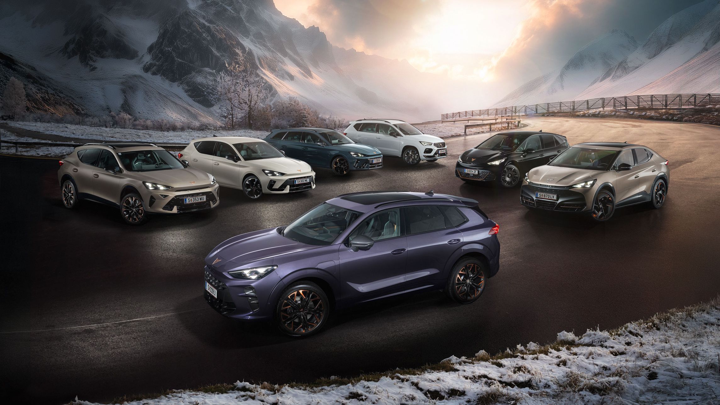 Eine Gruppe von CUPRA Fahrzeugen stehen auf einer verschneiten Straße vor einer malerischen Berglandschaft bei Sonnenuntergang. Es sind verschiedene Modelle in unterschiedlichen Farben. Im Hintergrund sind hohe, schneebedeckte Berge und dramatische Wolkenformationen zu sehen.