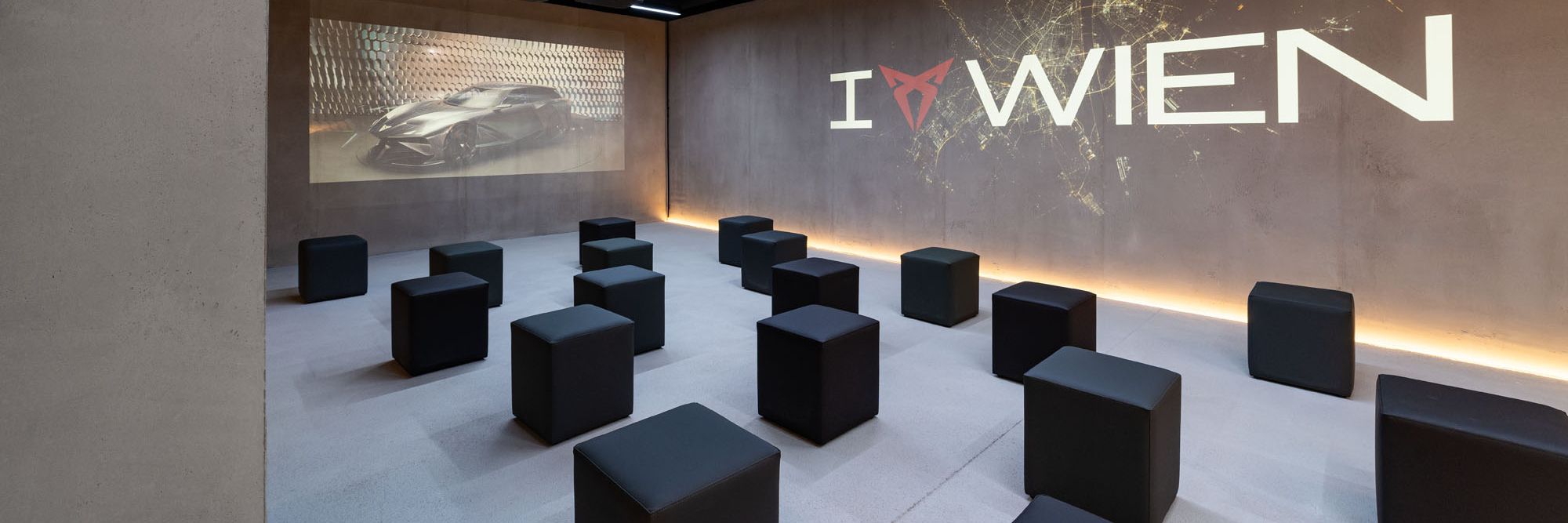 Raum mit Würfel-Sesseln und I CUPRA Wien Logo an der Wand