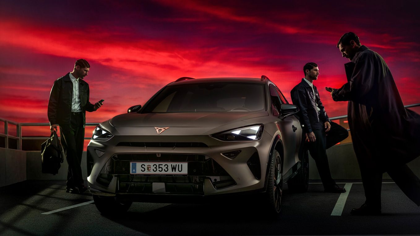 Drei Business-Männer stehen um den CUPRA Formentor bei Abendrott