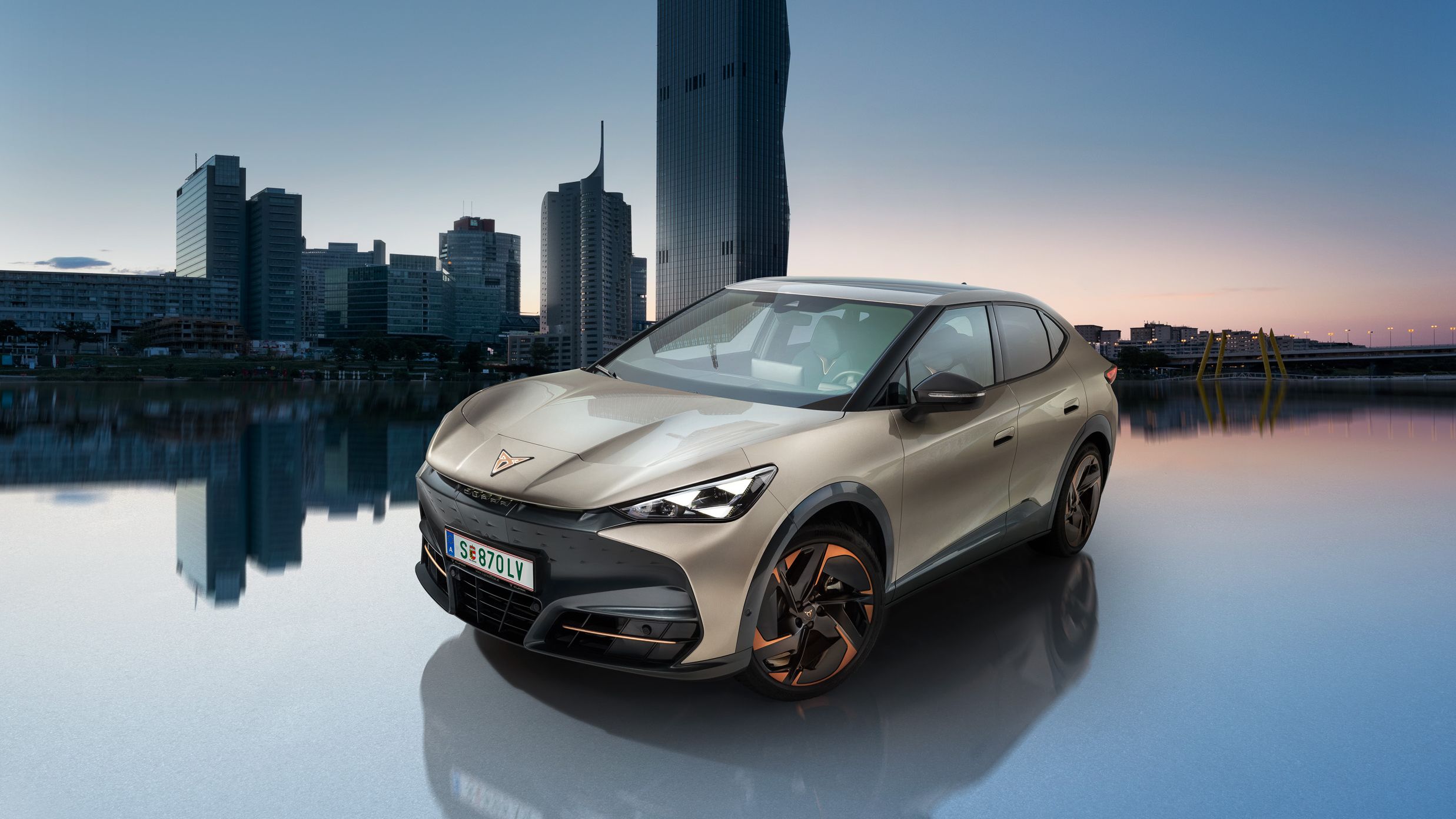 Der CUPRA Tavascan in Atacama Beige mit der Wiener Donau im Hintergrund