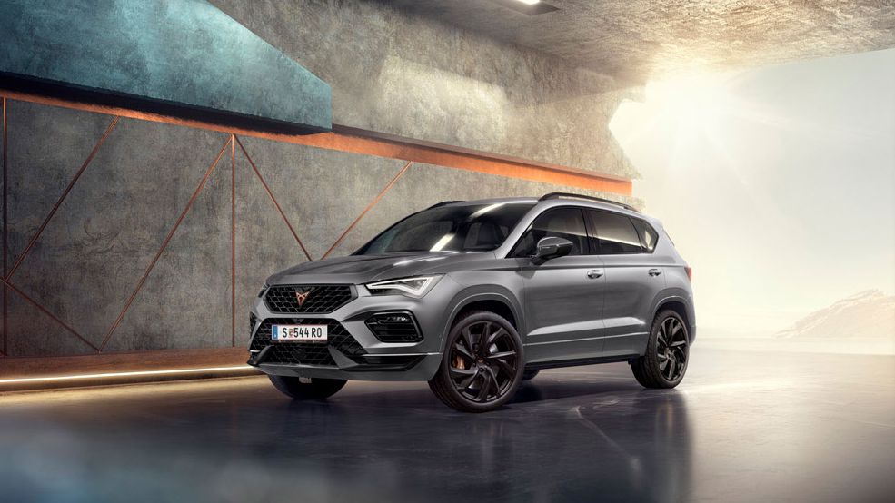 Ein CUPRA Ateca 2025 in Graphitgrau, ein sportliches und kompaktes SUV, geparkt in einer modernen, industriellen Umgebung.