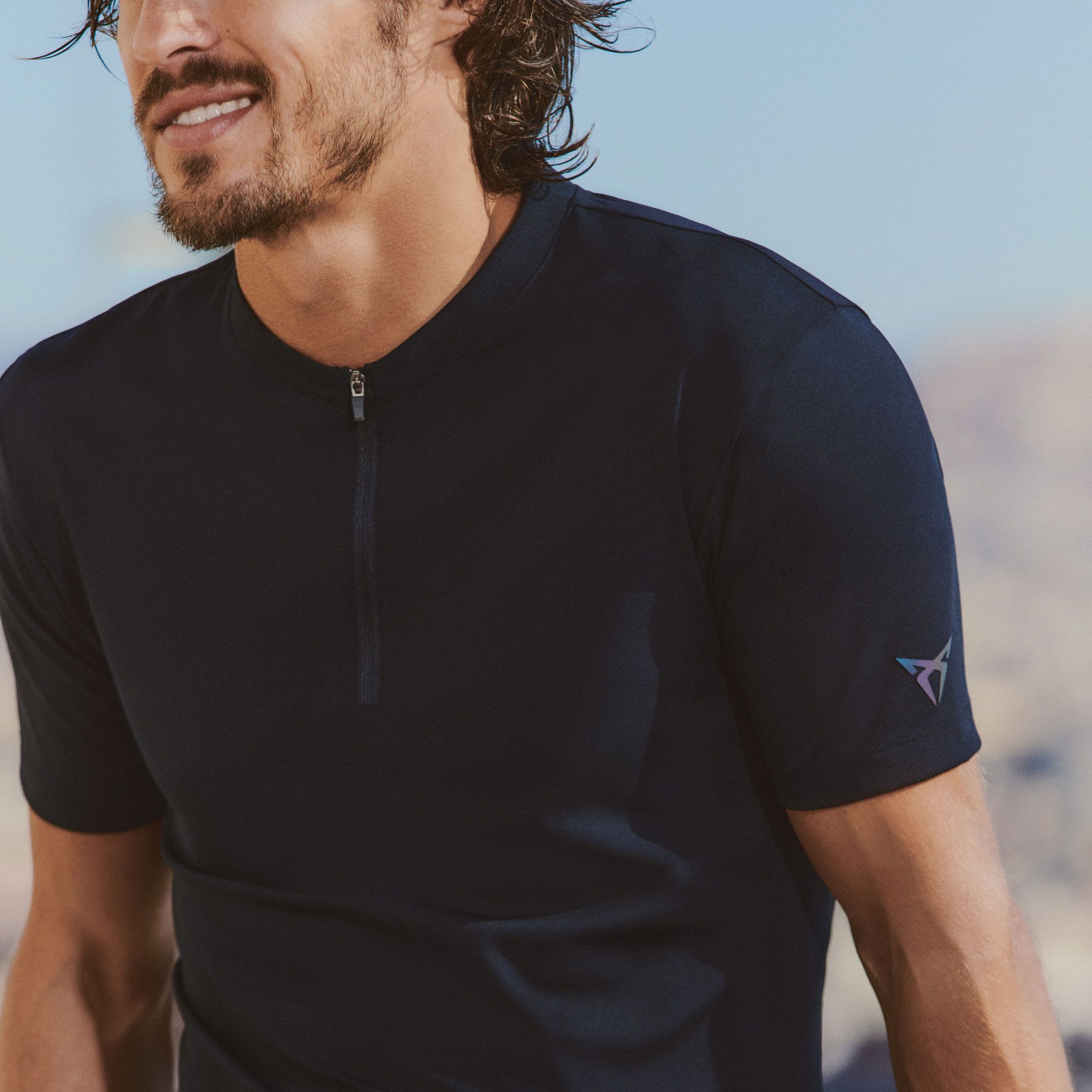 Ein Mann trägt ein blaues Shirt und eine Badehose von CUPRA Lifestyle