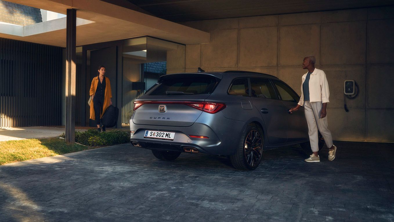 Eine Frau öffnet die Beifahrertür von einem CUPRA Leon SP Kombi.