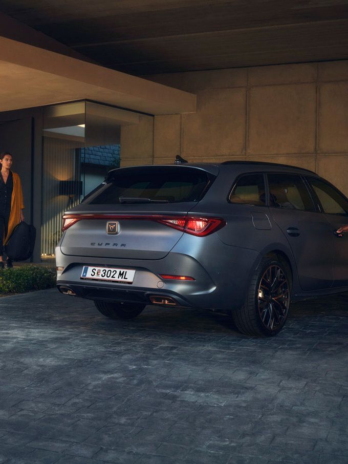 Eine Frau öffnet die Beifahrertür von einem CUPRA Leon SP Kombi.