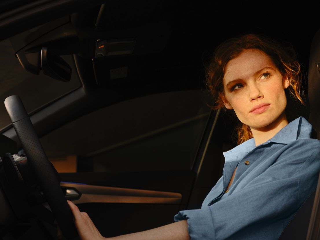 EIne Frau sitzt bei geöffneter Fahrertür am Steuer eines CUPRA Formentor