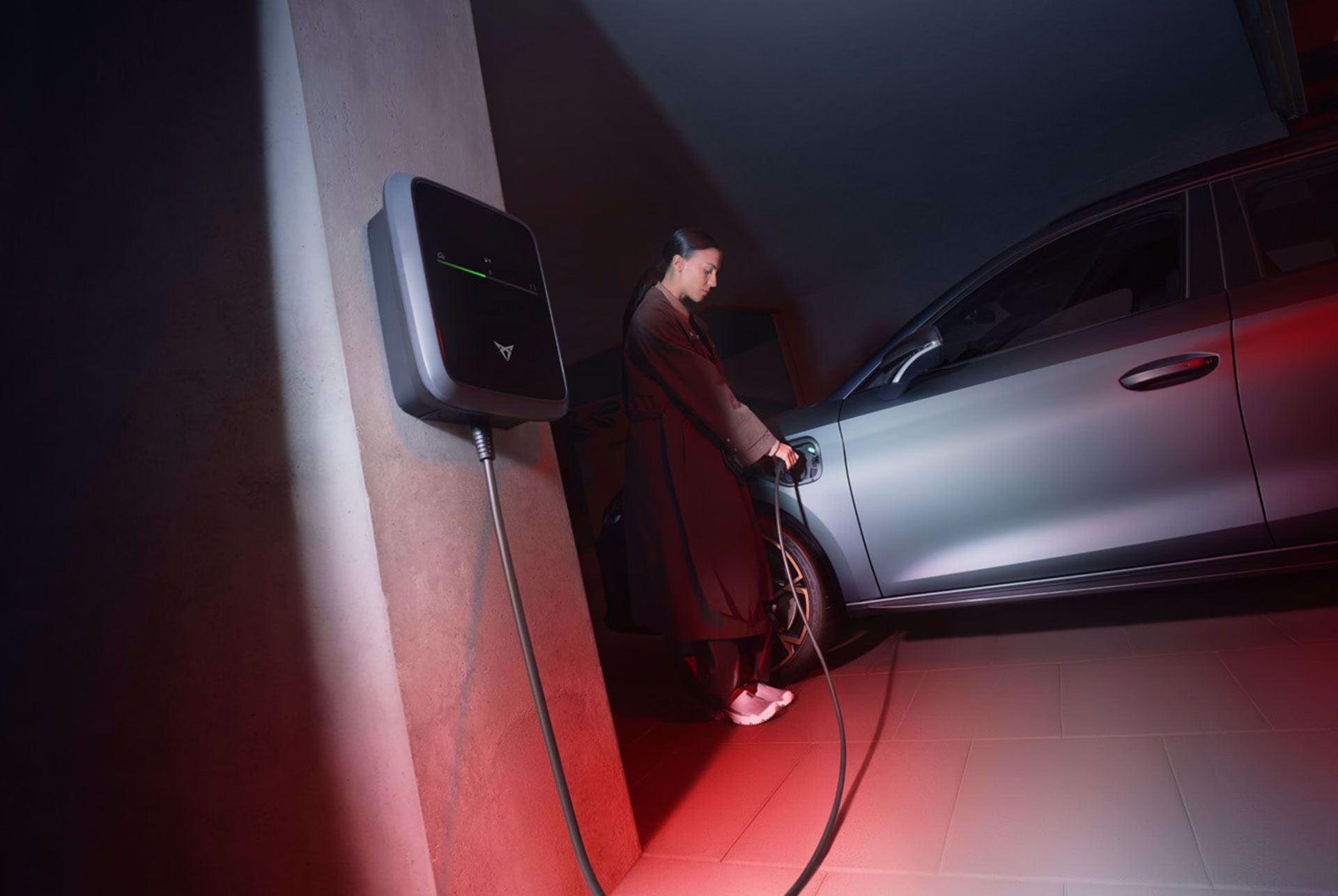 Eine Frau lädt einen grauen CUPRA Leon an einem CUPRA Charger.