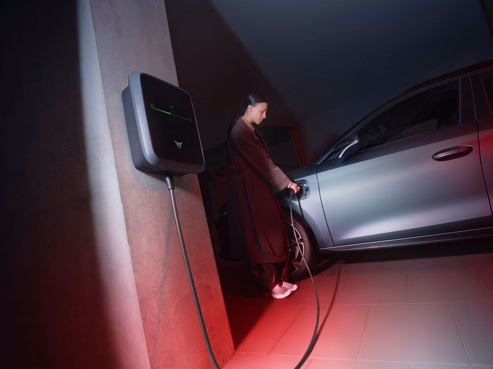 Eine Frau lädt einen grauen CUPRA Leon an einem CUPRA Charger.